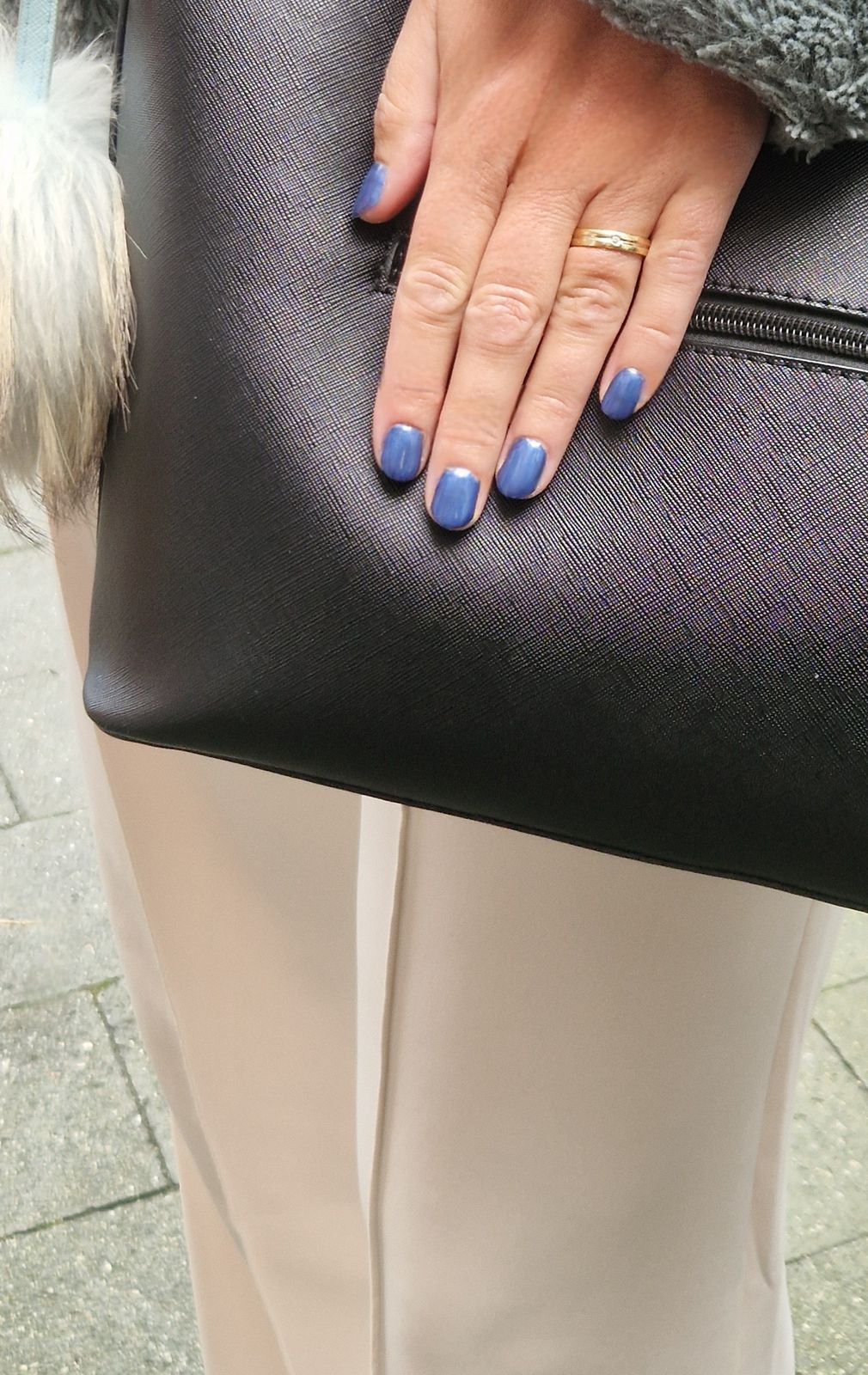 Lichtblauwe gellak op een hand met een zwarte tas
